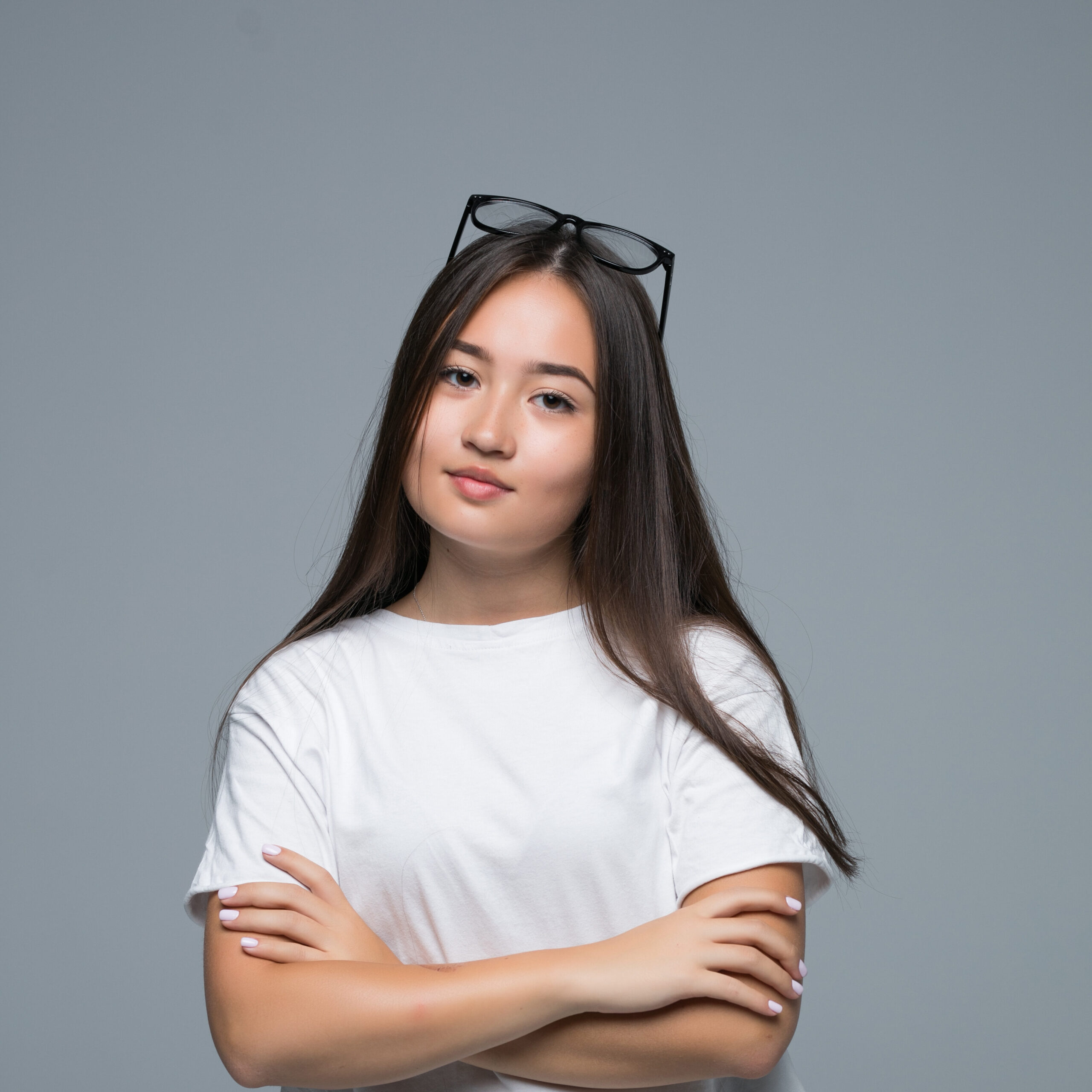 Testimonials emotion concept. portrait of angry cute asian woman standing posing with crossed arms looking at camera with grey clothes on a white background